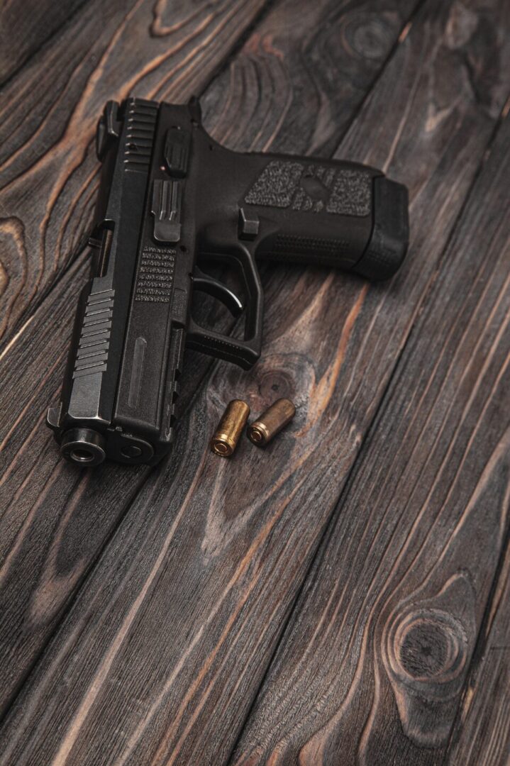 Pistol with bullets on wooden background representing firearms, ammo, and reloading.